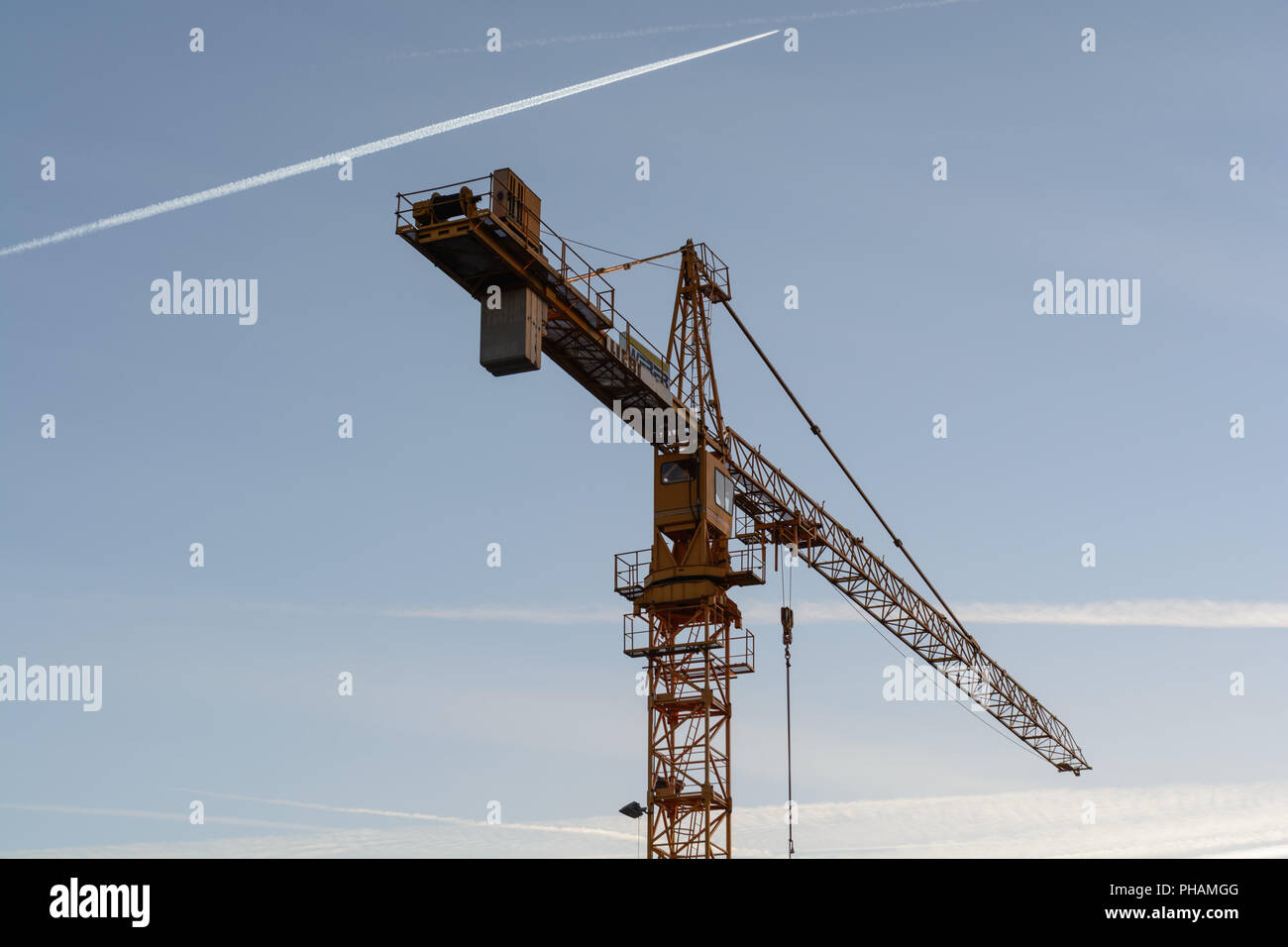 Imposing tower crane, blue sky with contrails Stock Photo