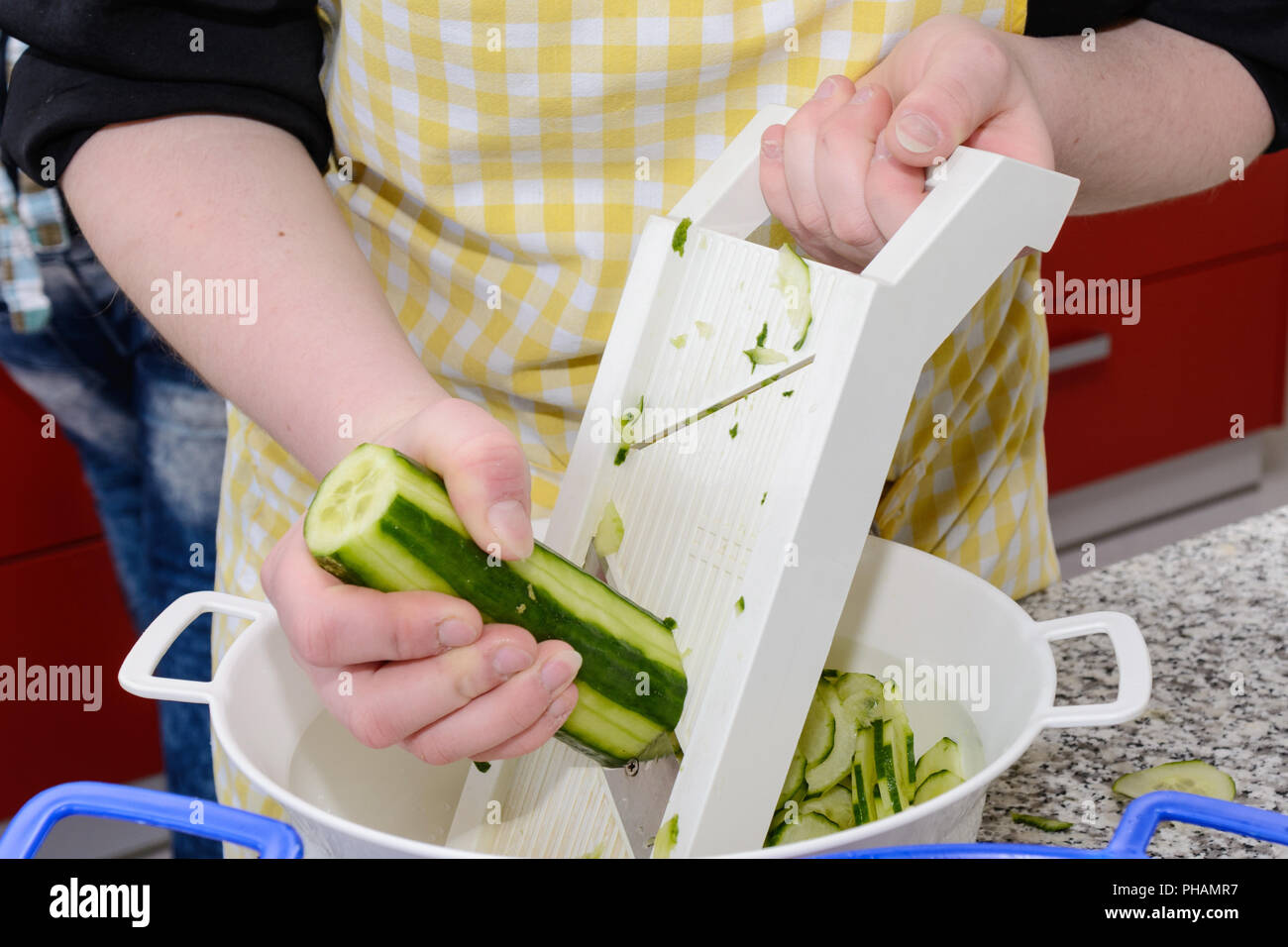 Cook cutting cucumber with vegetable slices for salad Stock Photo