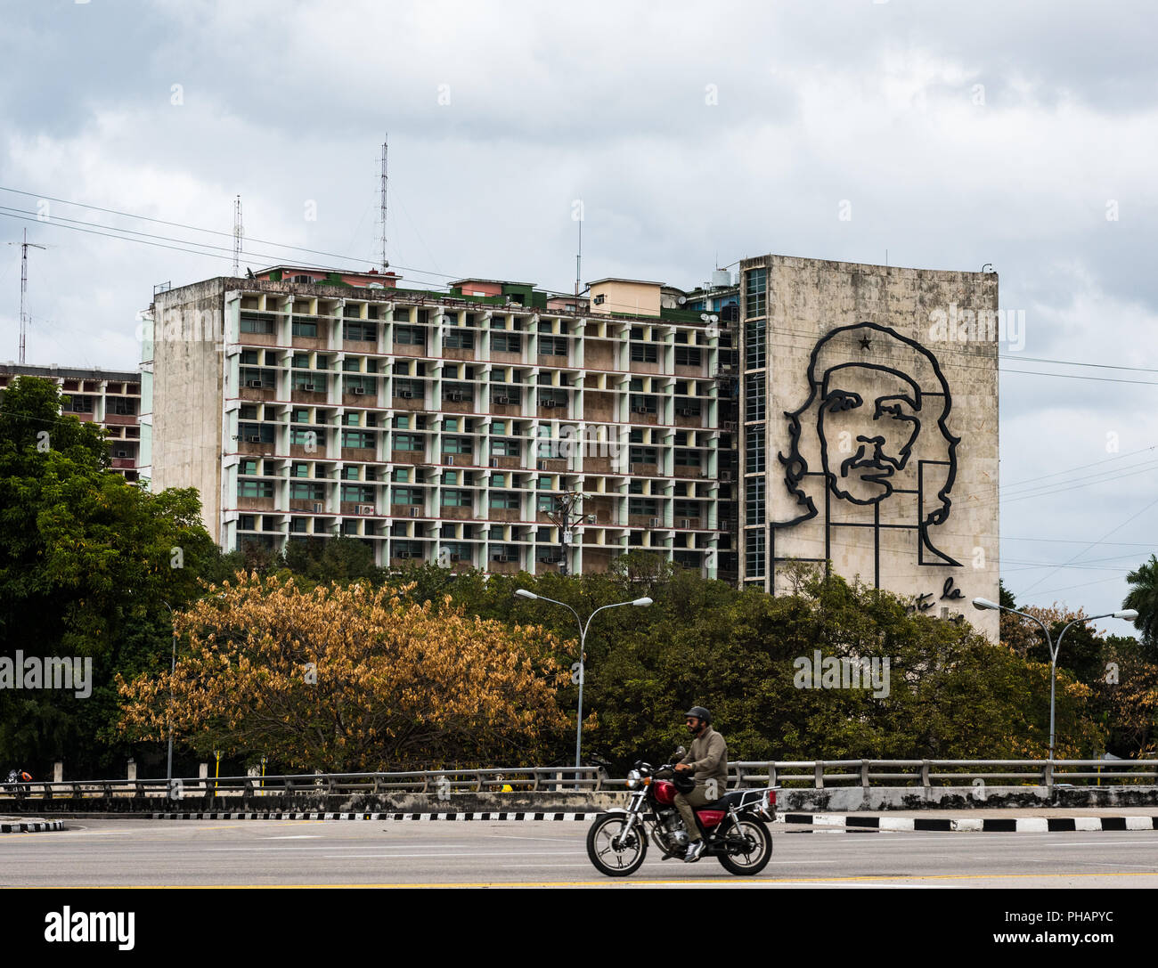 Motorcyclist passes Plaza Revolucion in Havana, Cuba where the Ministry of the Interior building sports an iron mural of guerilla leader Che Guevara. Stock Photo