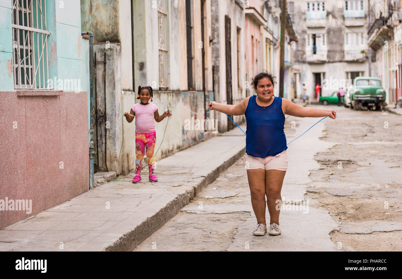 Havana, Cuba / March 22, 2016:  Happy smiling little girls playing with jump rope in Old Havana Alley. Stock Photo