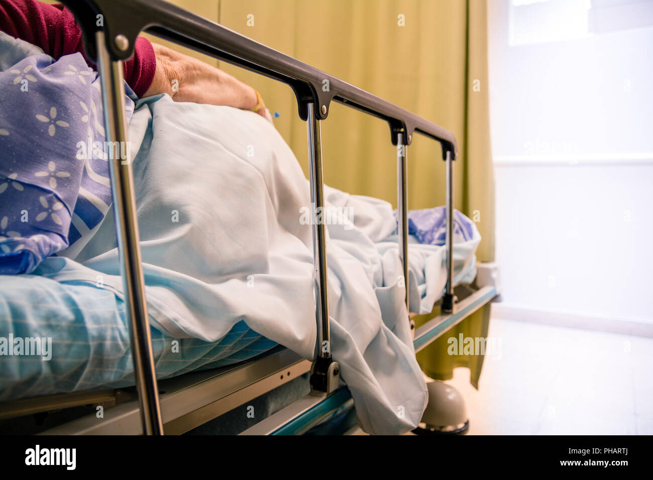 Woman patient lying on a bed in a hospital room Stock Photo