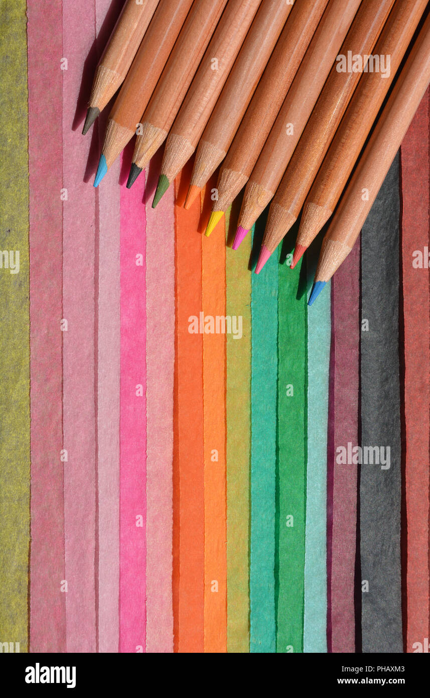 Colour pencils on a brightly coloured, striped,  tissue paper background with copy space. Stock Photo