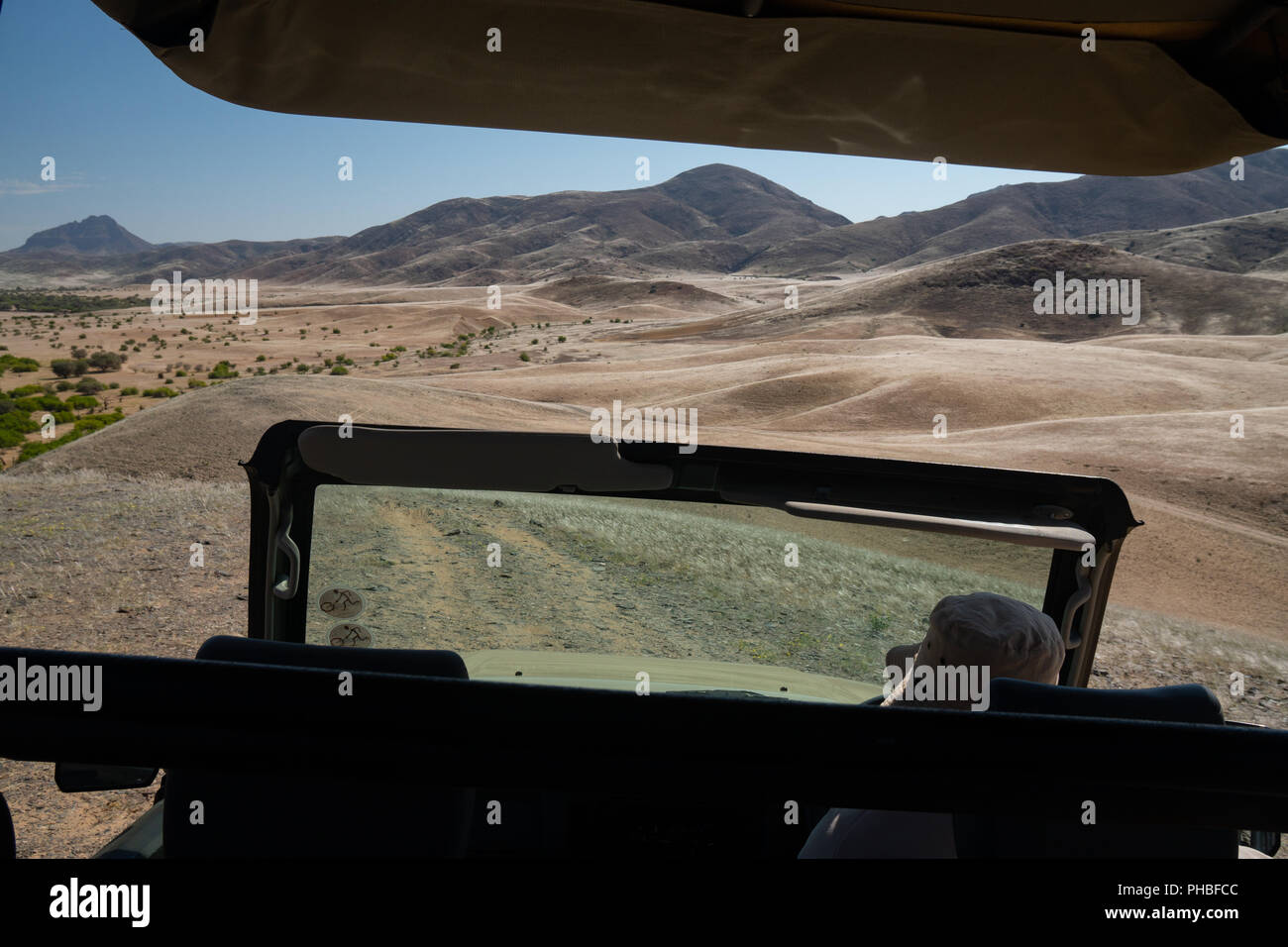 View over Hoarusib Riverbed from inside a safari vehicle, mountain range in background, Puros, north of Sesfontein, Nambia, Africa Stock Photo