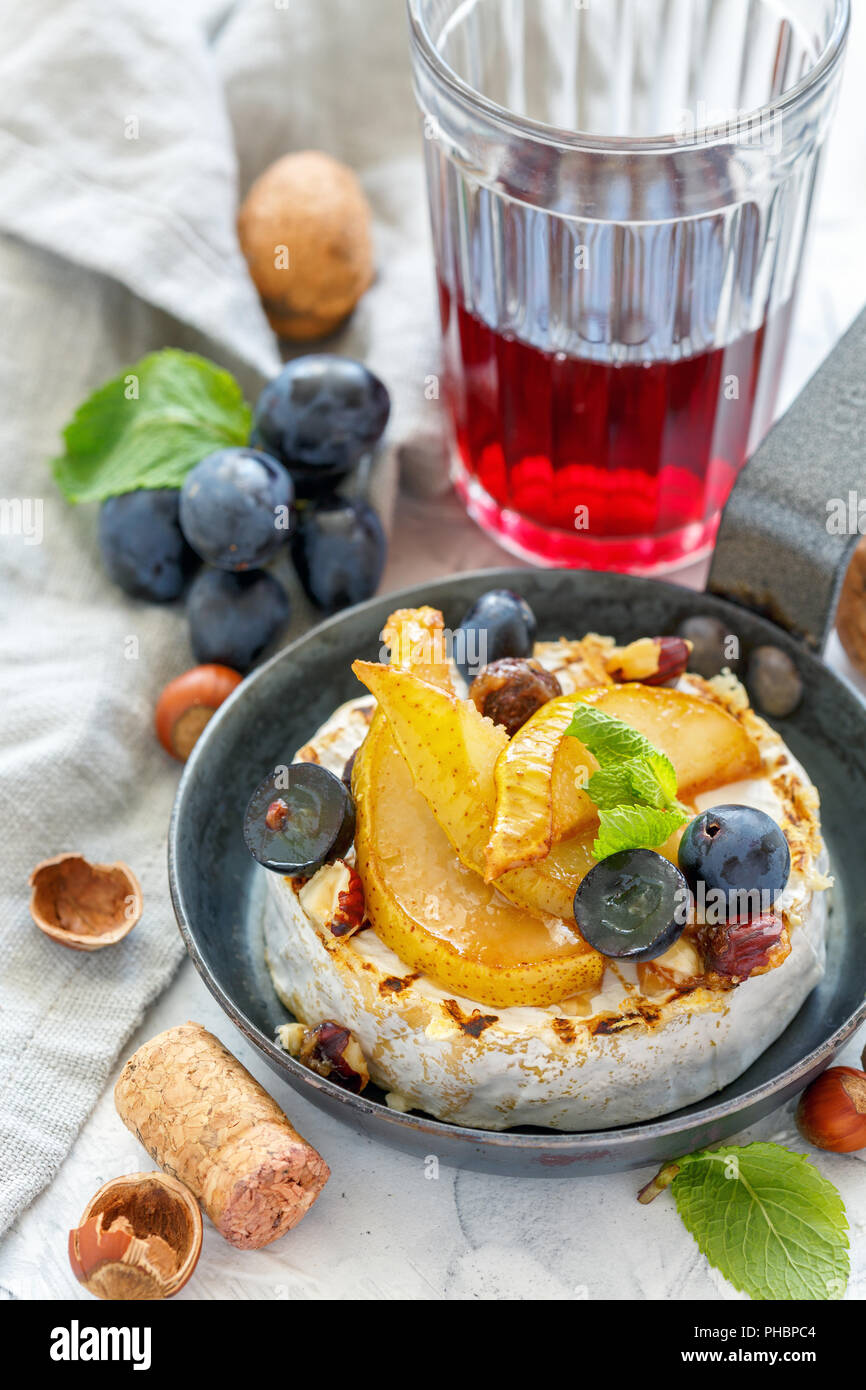 Baked camembert with pears, hazelnut and grapes. Stock Photo