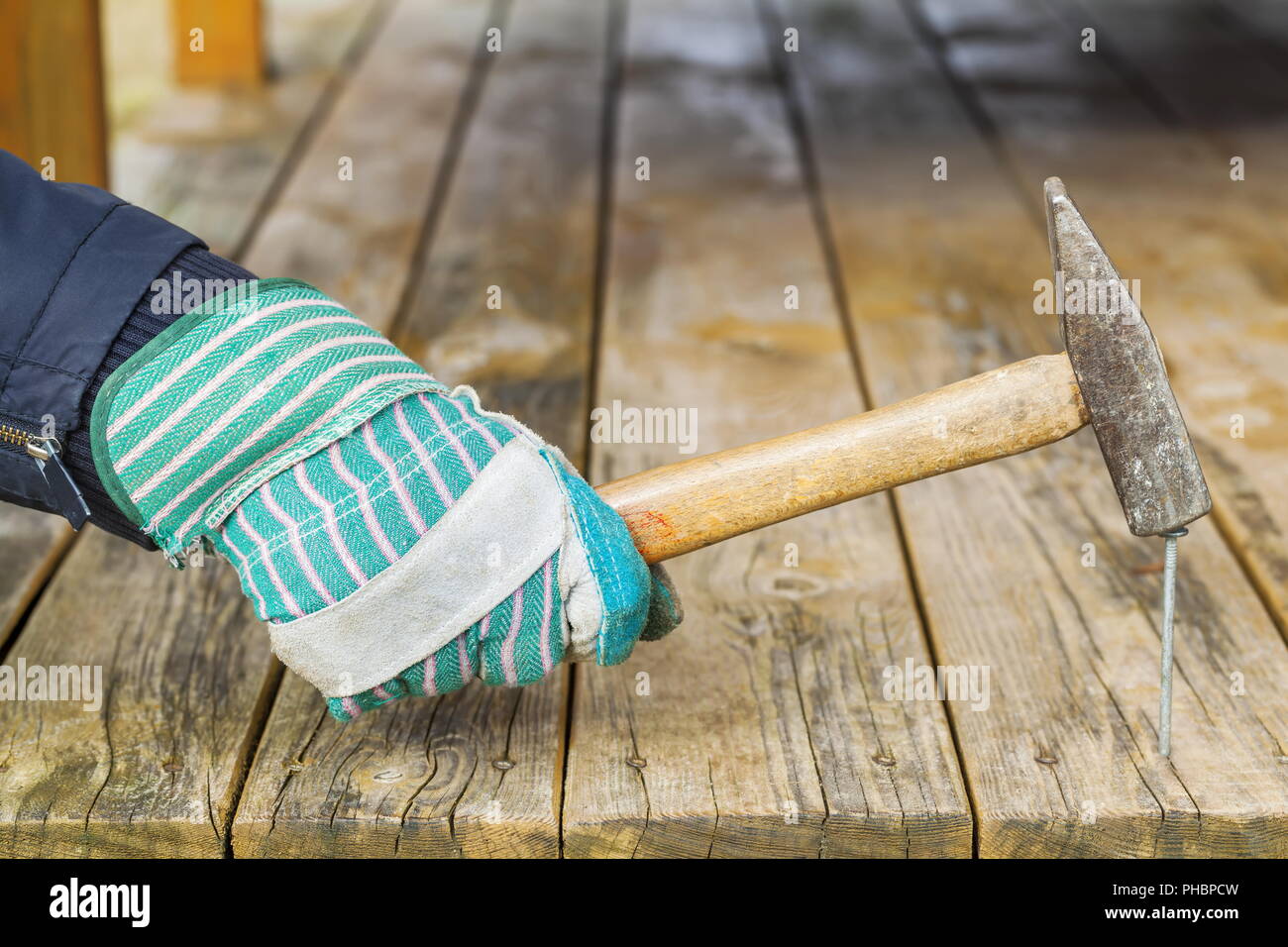 Worker hammering nail in wooden board Stock Photo