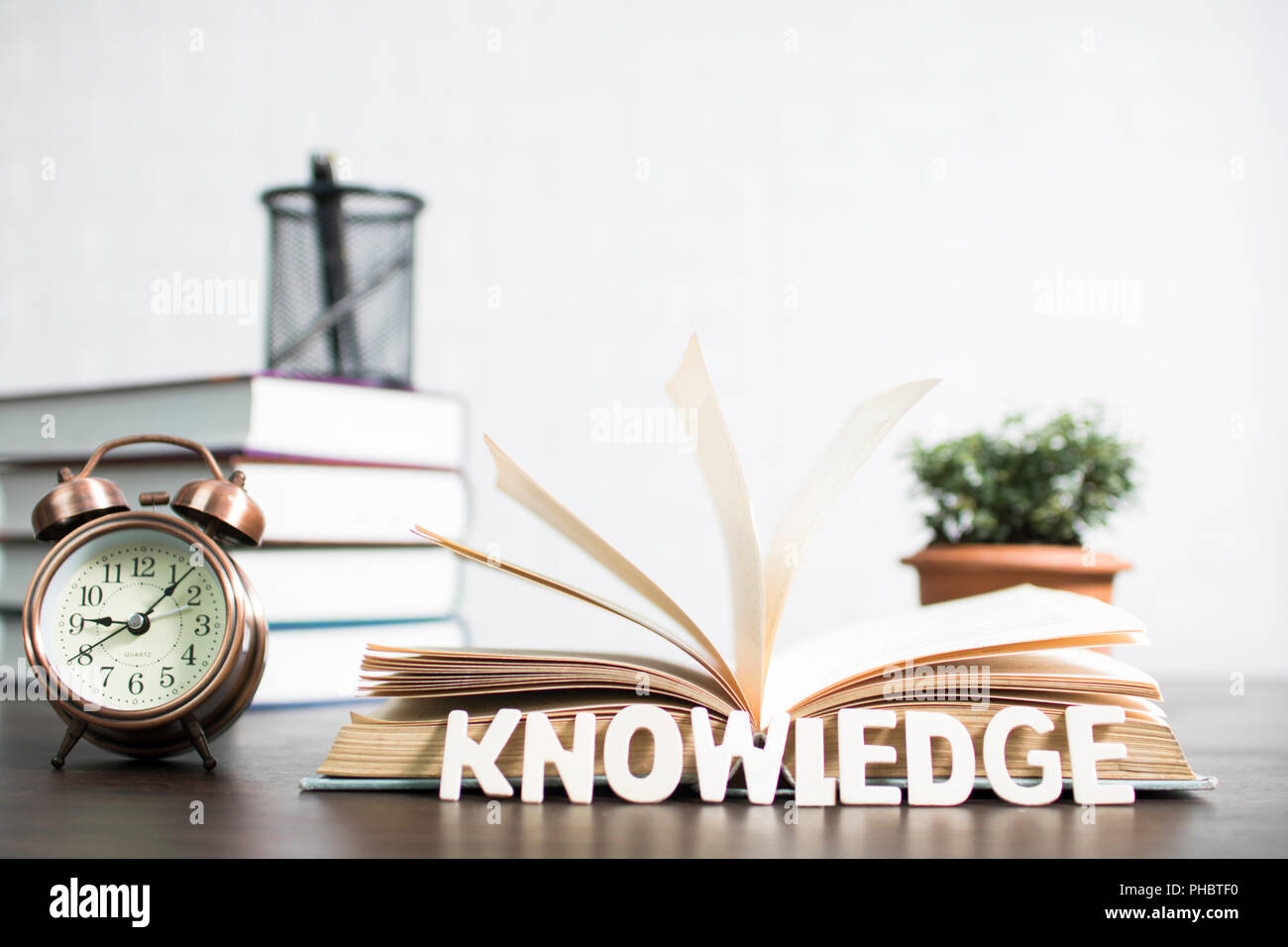 books and clock with plant growing up on table, knowledge and education concept Stock Photo