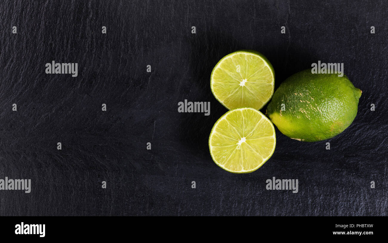 Overhead view of organic limes on black slate background Stock Photo