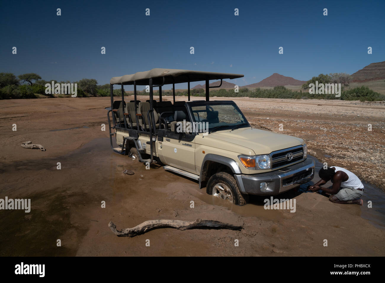Guide tries to jack up safari vehicle stuck in the sand of Hoarusib Riverbed, Puros, north of Sesfontein, Nambia, Africa Stock Photo