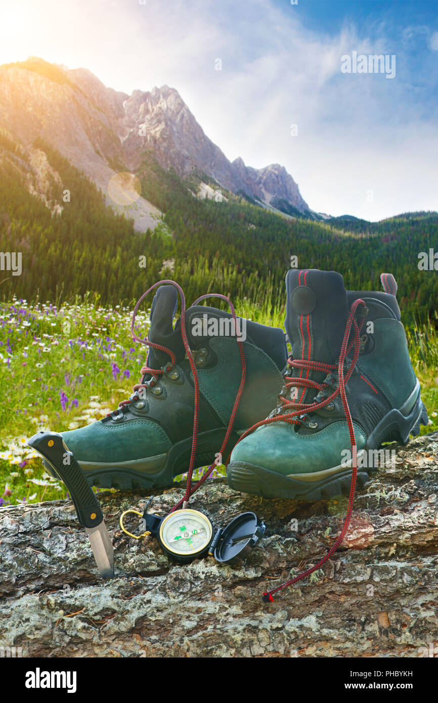 Hiking boots with knife on tree trunk Stock Photo - Alamy