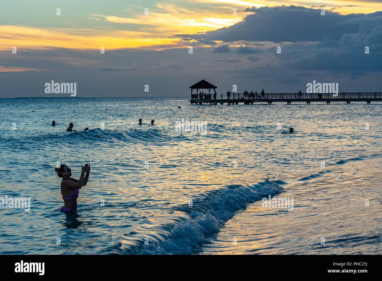 Bayahibe, Dominican Republic, 26 August 2018. A woman takes a selfie from the warm waters at sunset while vacationing at a Caribbean resort in the Dom Stock Photo