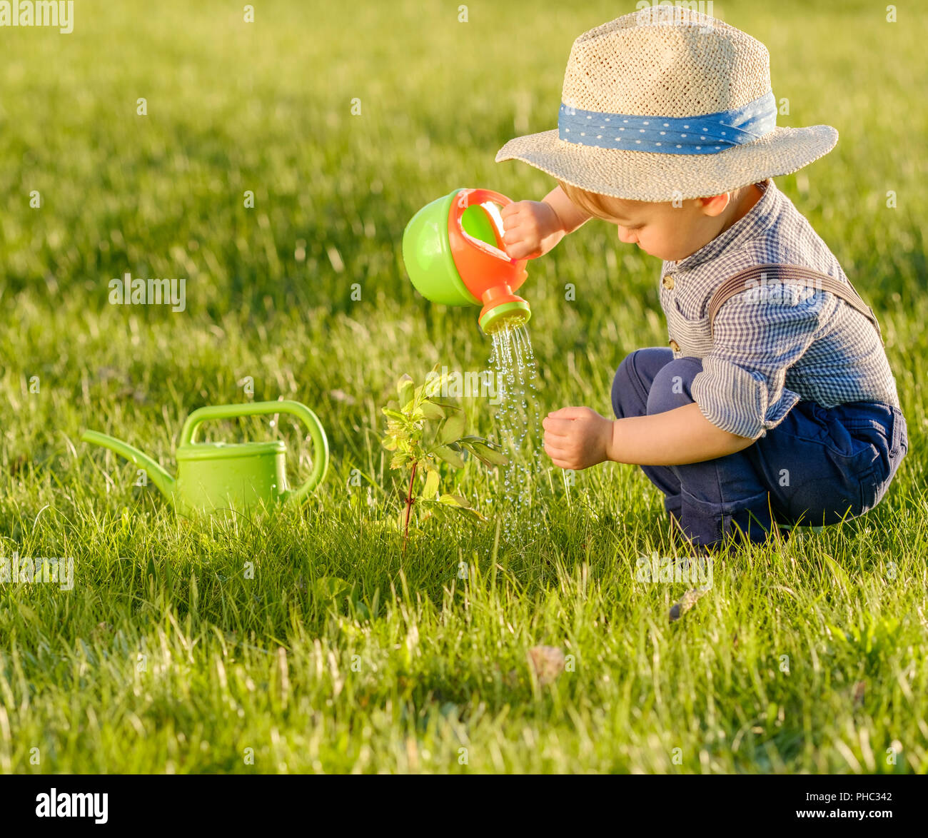 Toddler child outdoors. One year old baby boy wearing straw hat using