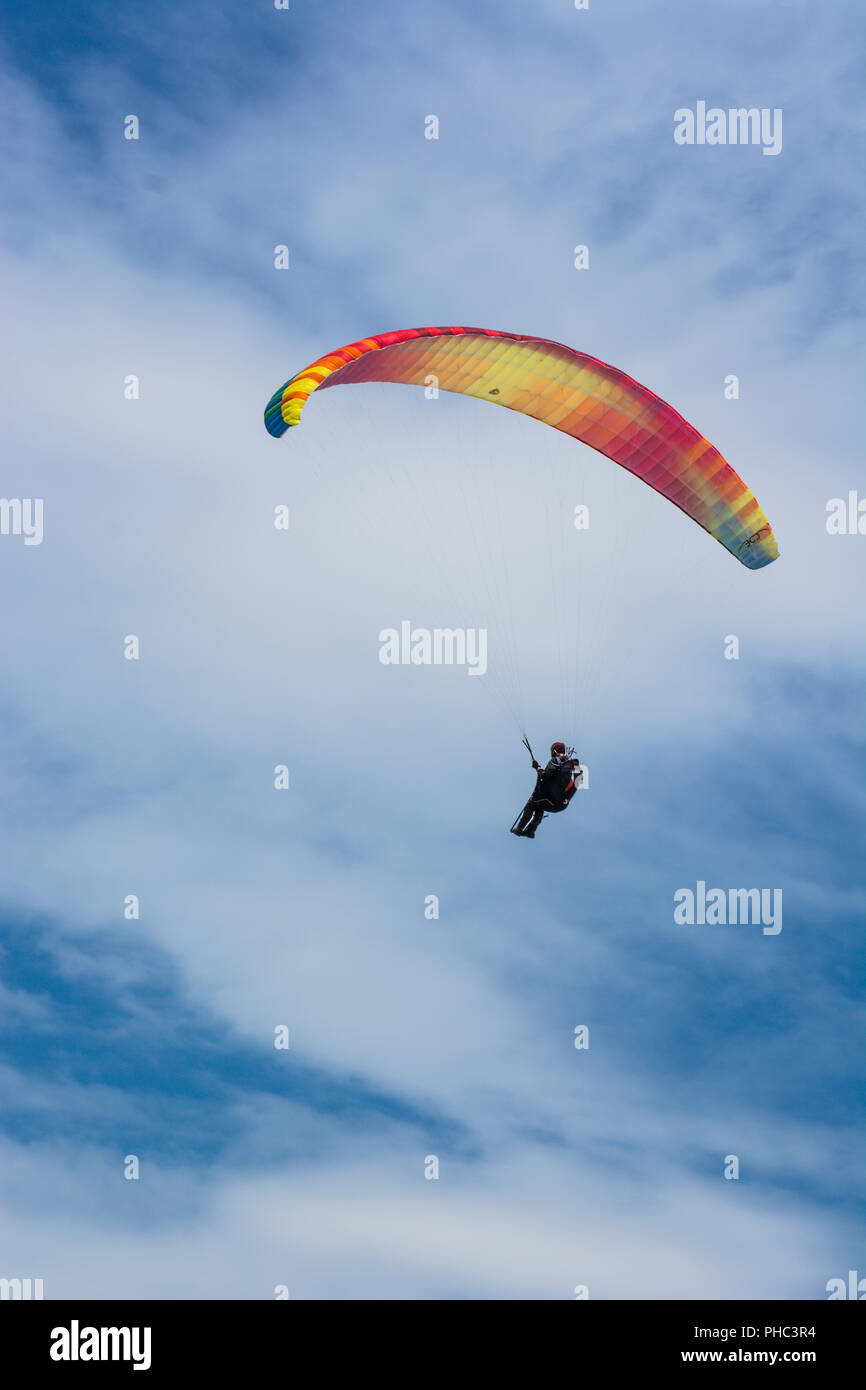 Paraglider flies in the blue summer sky Stock Photo