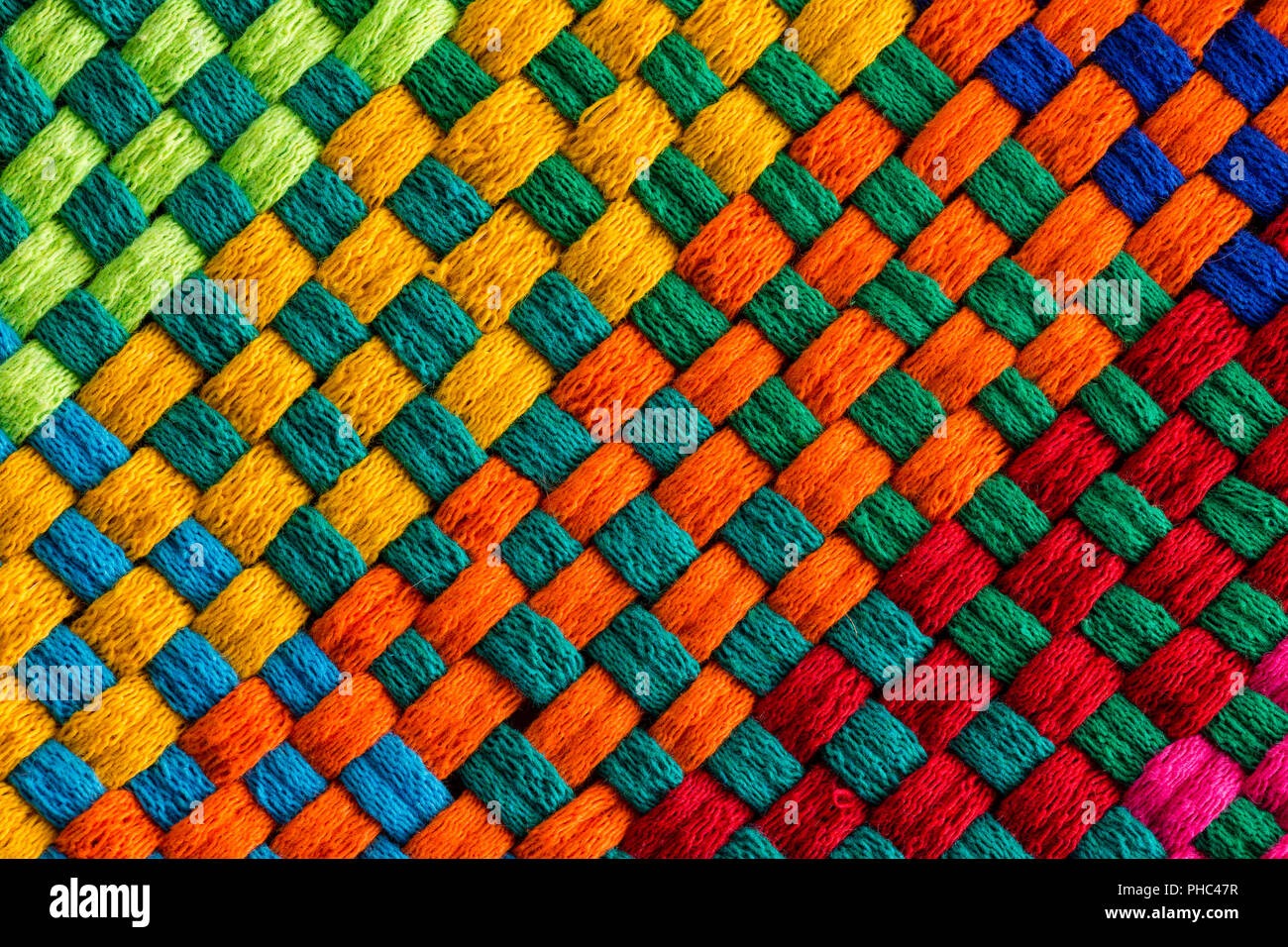 Background completely covered by diagonally angled rainbow colored interweaving threads of stitched fabric Stock Photo