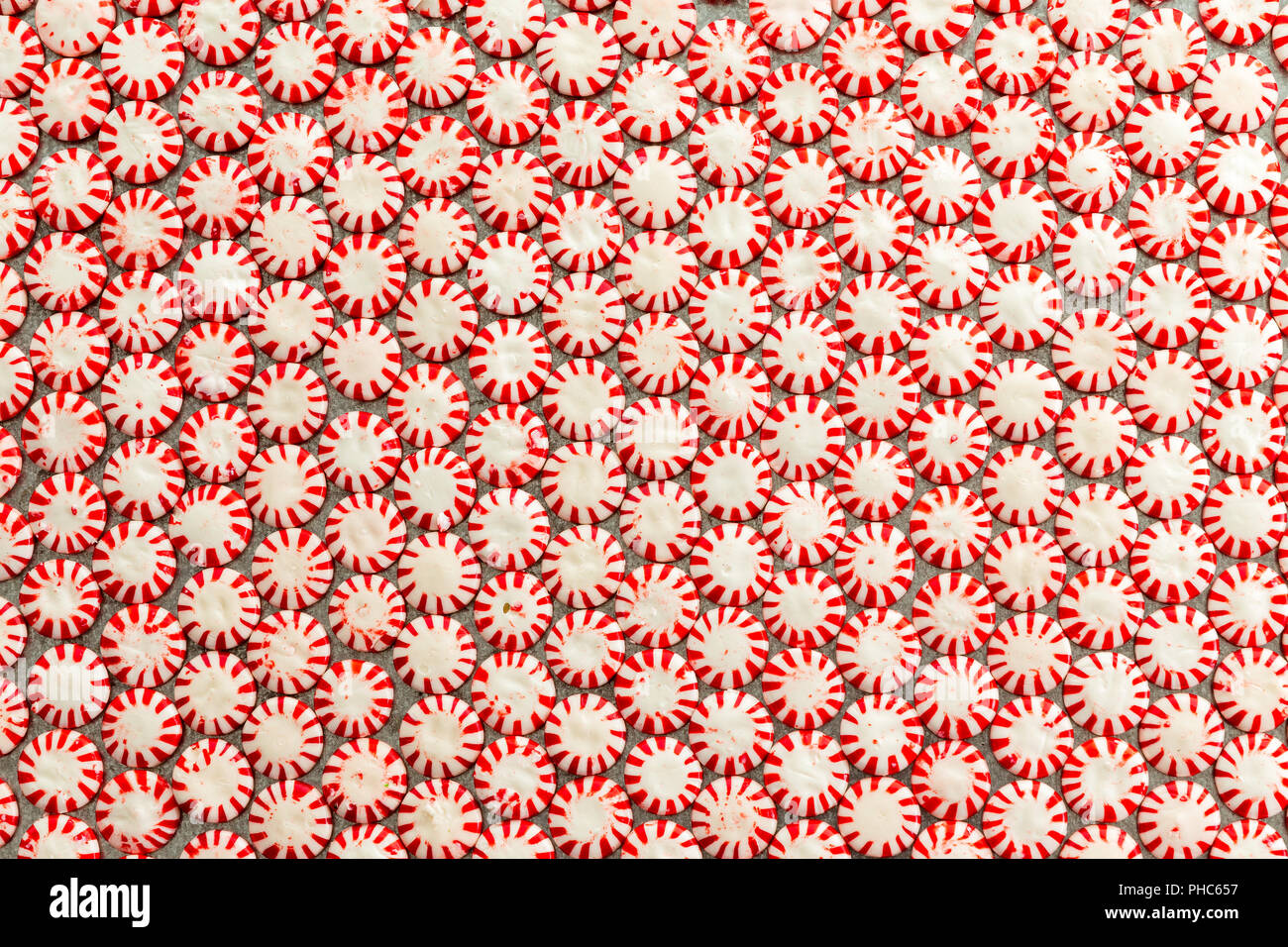 Background texture and pattern of colorful striped red and white peppermint flavored starlight candies packed closely together in a neat layer viewed  Stock Photo