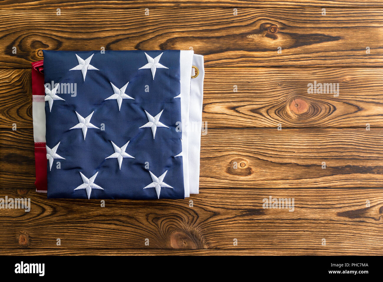 Neatly folded American flag showing the stars representing the original 13 colonies on a wooden table viewed from overhead with copy space Stock Photo