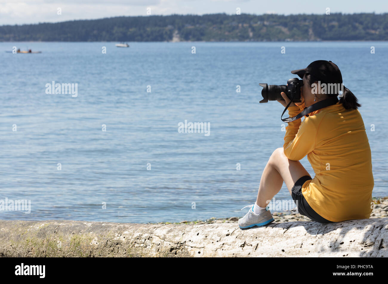 Woman photographer taking photos of calm lake during summer time Stock Photo