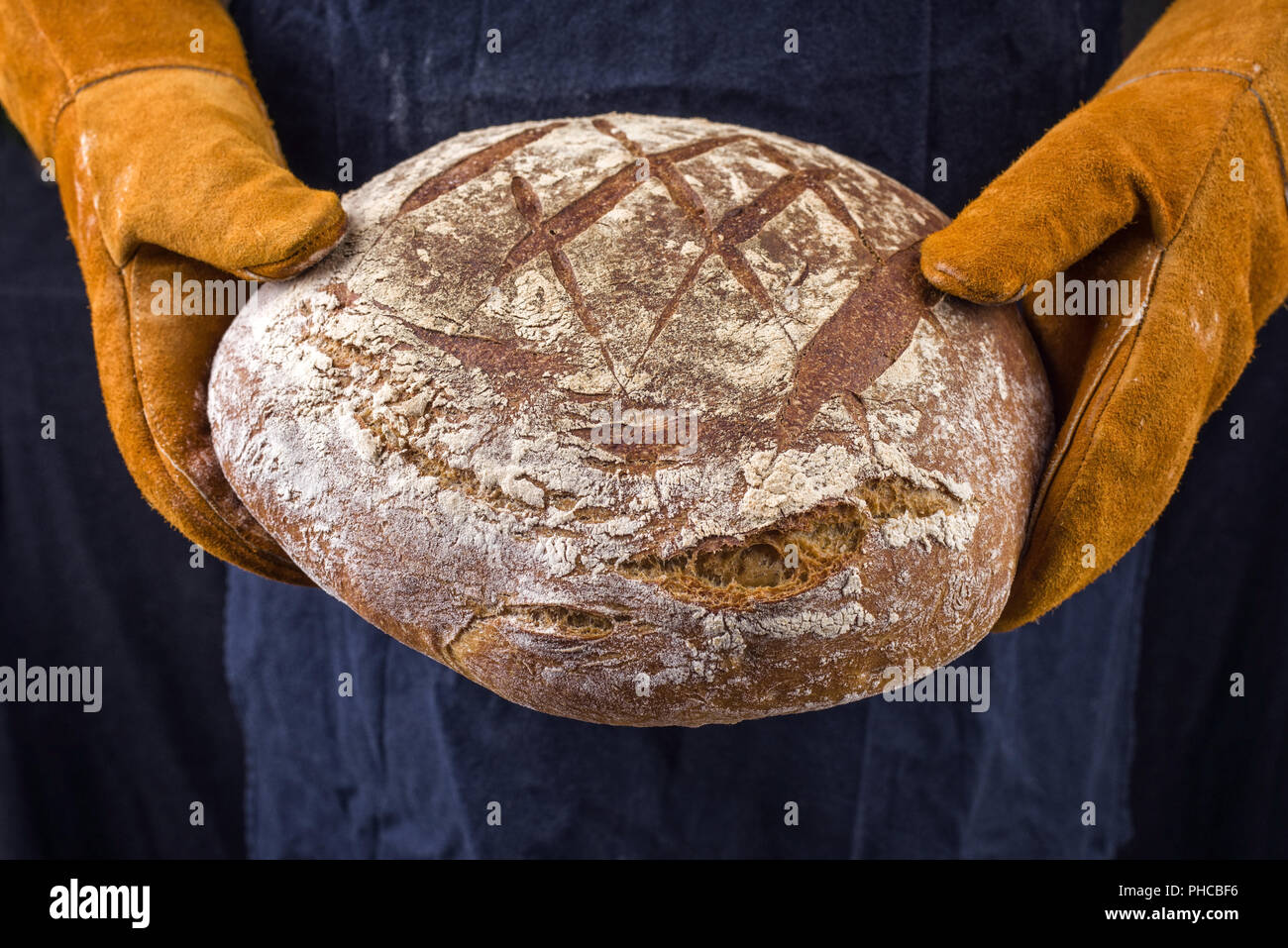 Freshly backed Farmhouse Bread hold in hand with oven gloves Stock