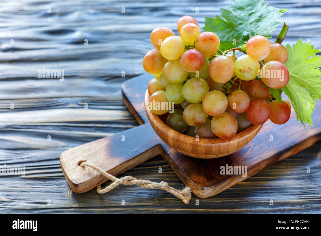 Bunch of pink grapes in wooden toe. Stock Photo