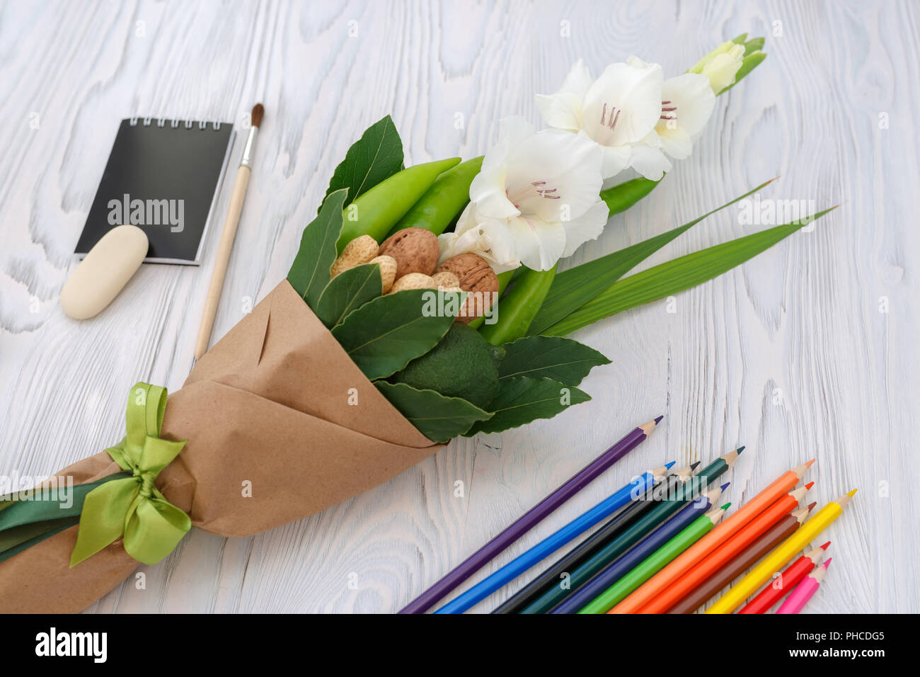 Small bouquet consisting of gladiolus, nuts, colour pencils and