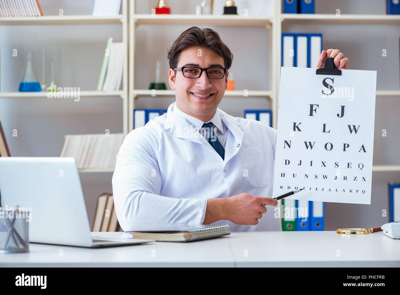 Doctor optician with letter chart conducting an eye test check Stock