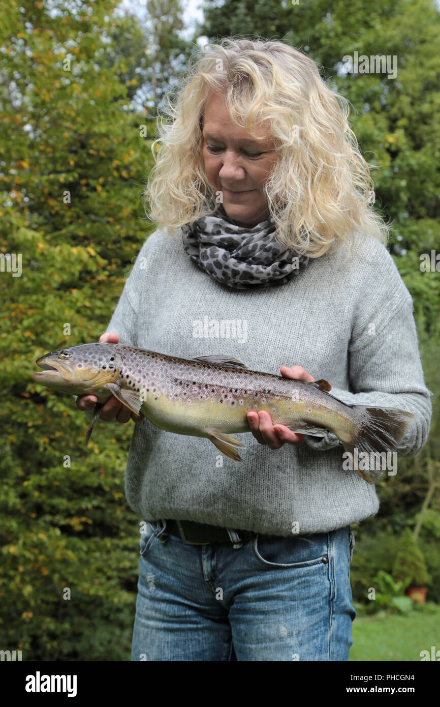 Woman presents a brown trout, Salmo trutta fario Stock Photo