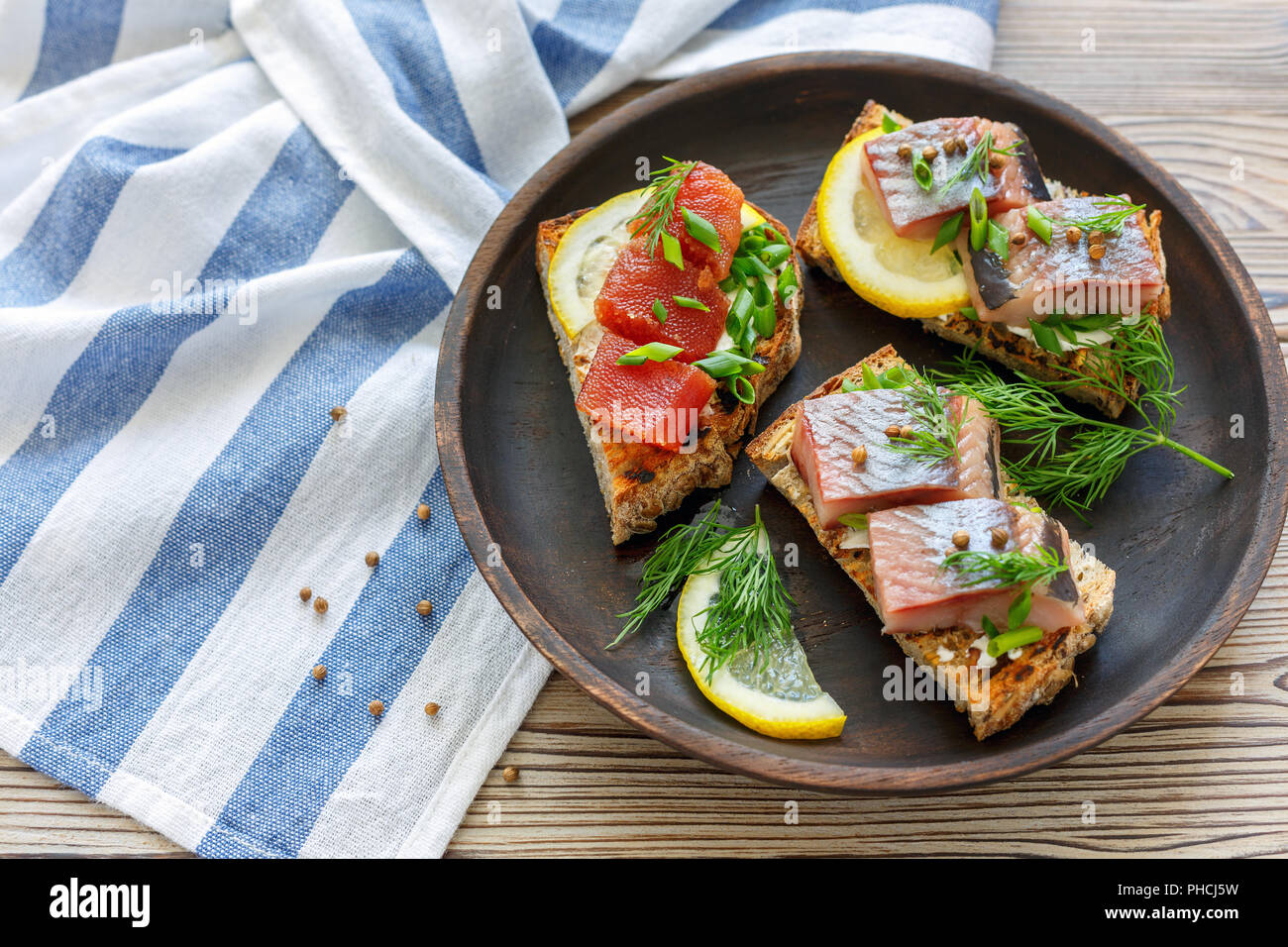 Grilled bread with chunks of herring, caviar and chives. Stock Photo
