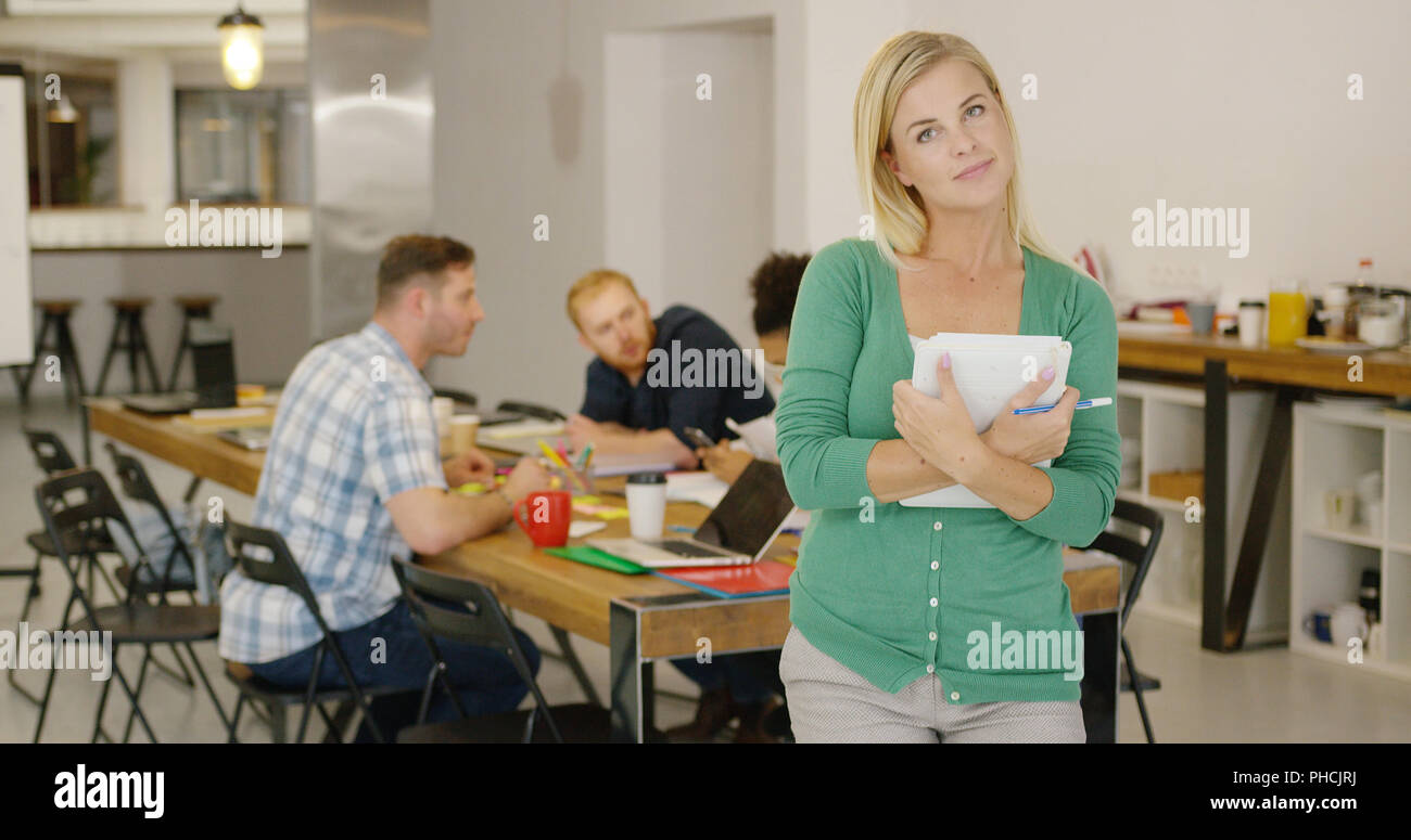 Confident woman in office with coworkers Stock Photo