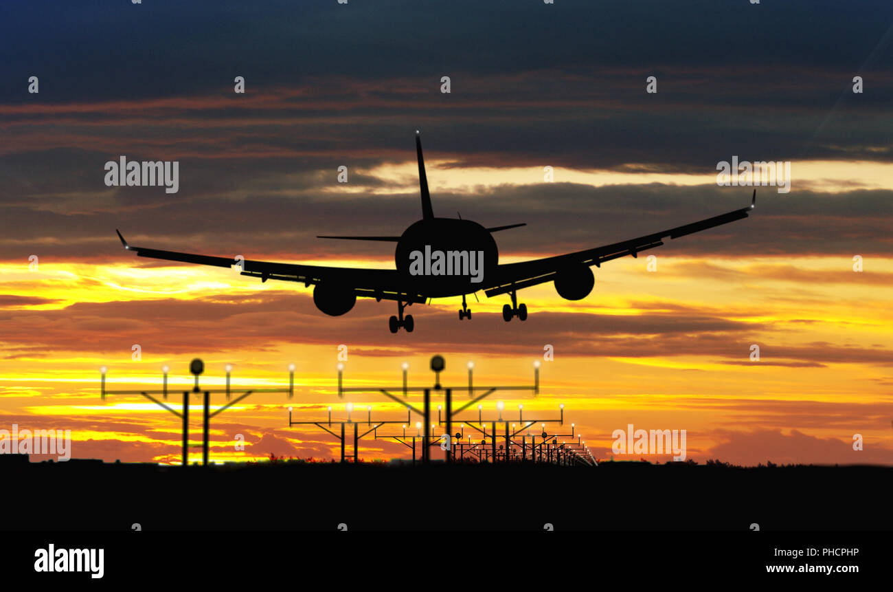 Silhouette airplane during landing on sunset sky in background. Jet plane arrival on airport. Stock Photo
