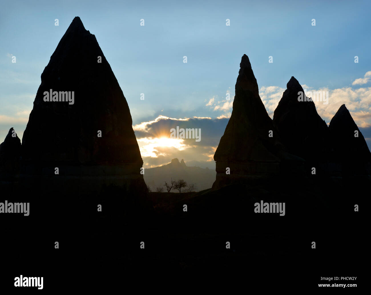 Fairy Chimneys silhouetted against the sunset in the Rose Valley, with Uchisar in the background, Cappadocia, Turkey Stock Photo