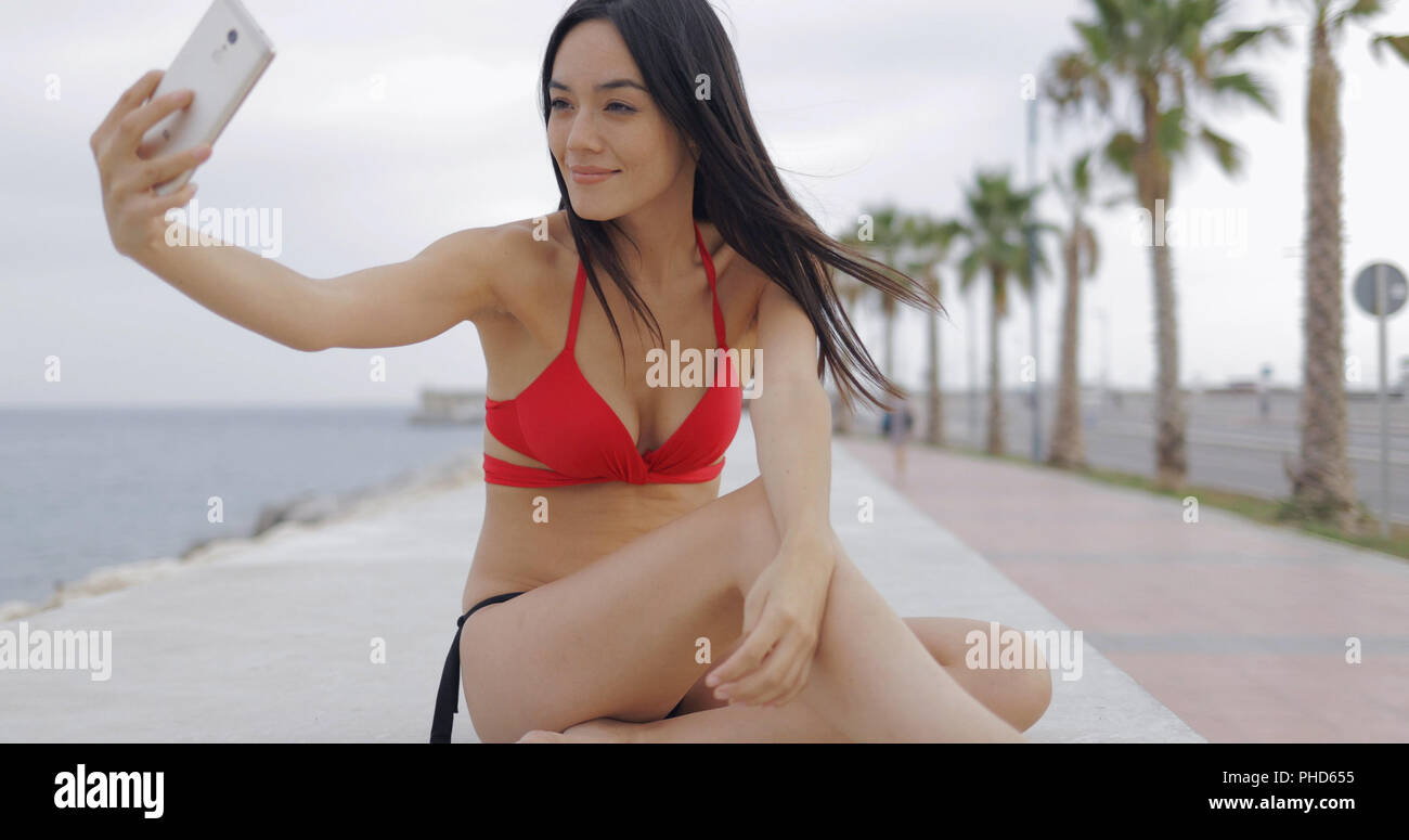 Stylish model taking selfie on tropical seafront Stock Photo