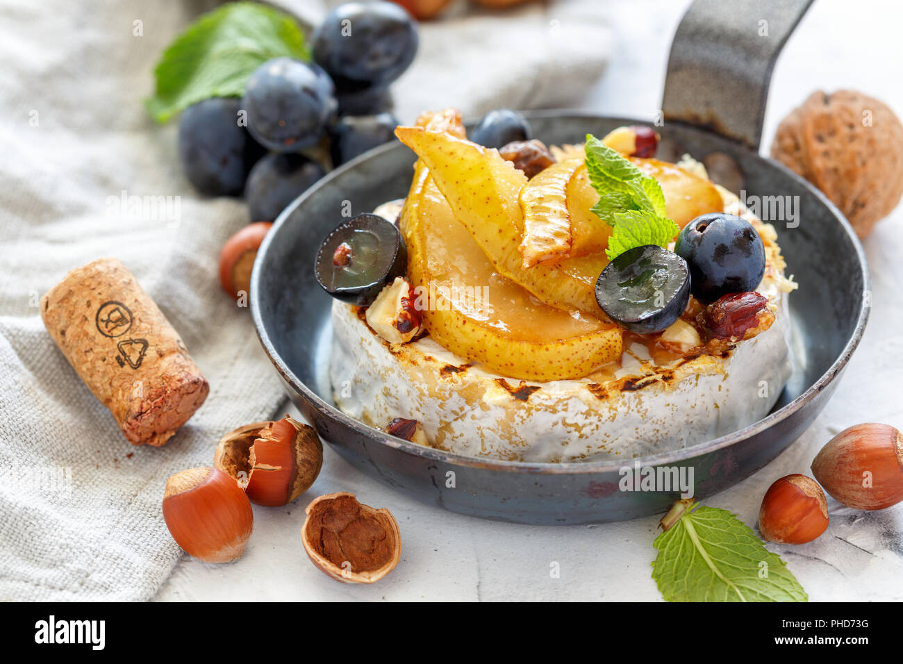 Grilled camembert with pears and black grapes. Stock Photo
