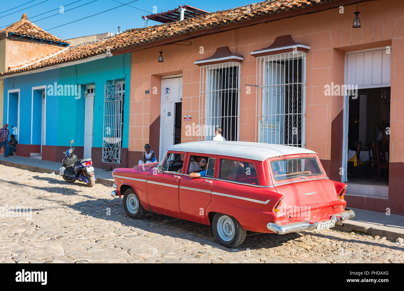 Trinidad, Cuba / March 15, 2016: Bright red vintage station wagon parked on cobble street of UNESCO World Heritage city Trinidad, Cuba. Stock Photo