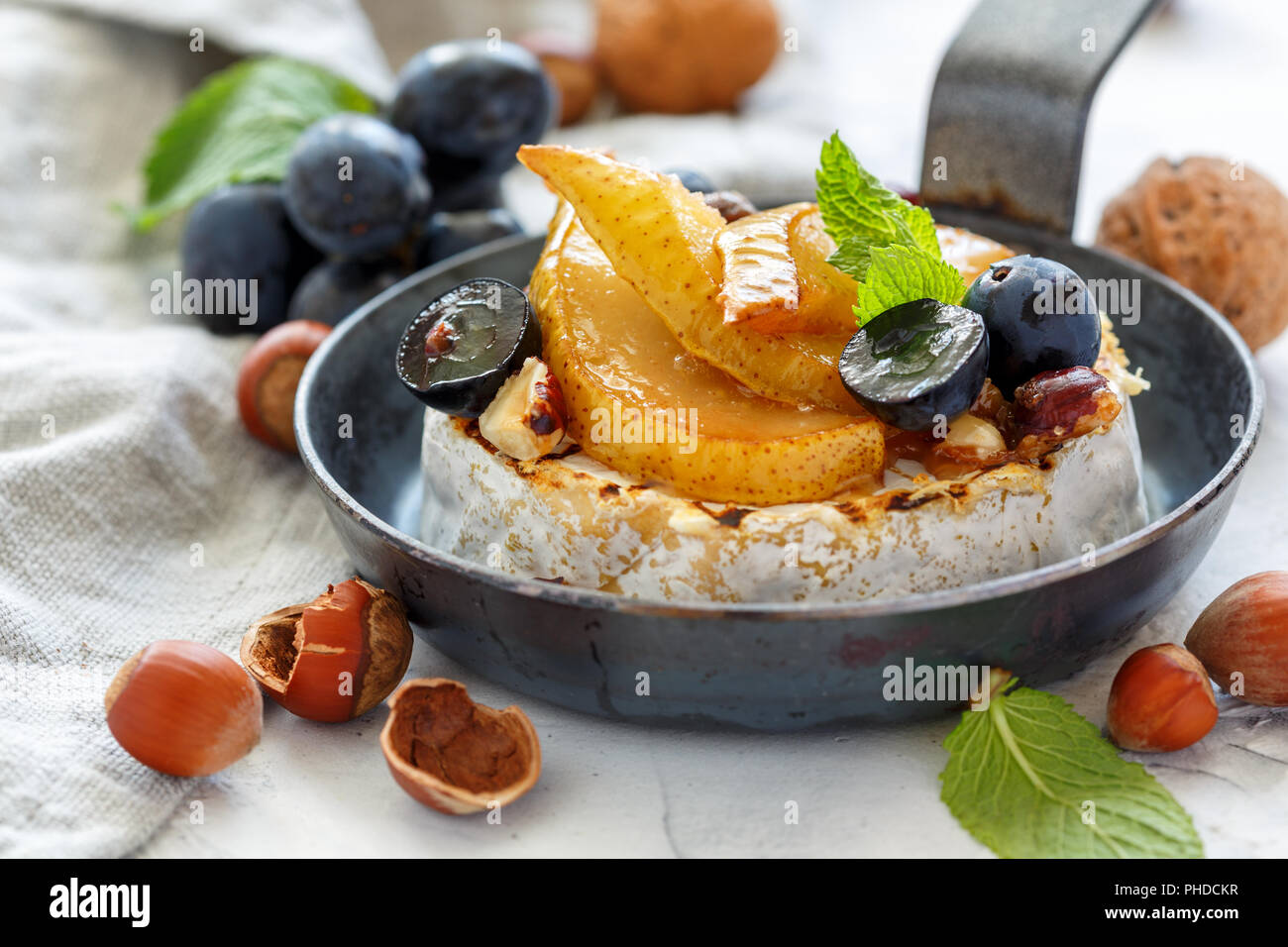 Grilled camembert with pears and black grapes. Stock Photo