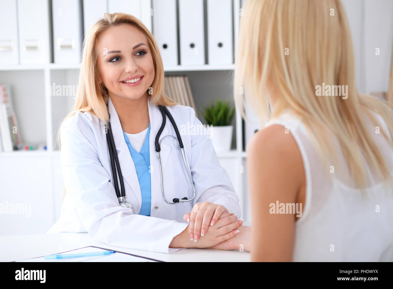 Doctor woman reassuring her female patient while holding hands ...