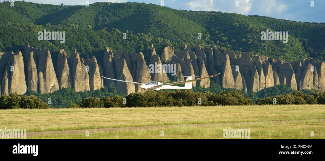 Sailplane on final approach with the rock formation of les Mées in the background. Château-Arnoux-Saint-Auban Airfield, Provence, France. Stock Photo