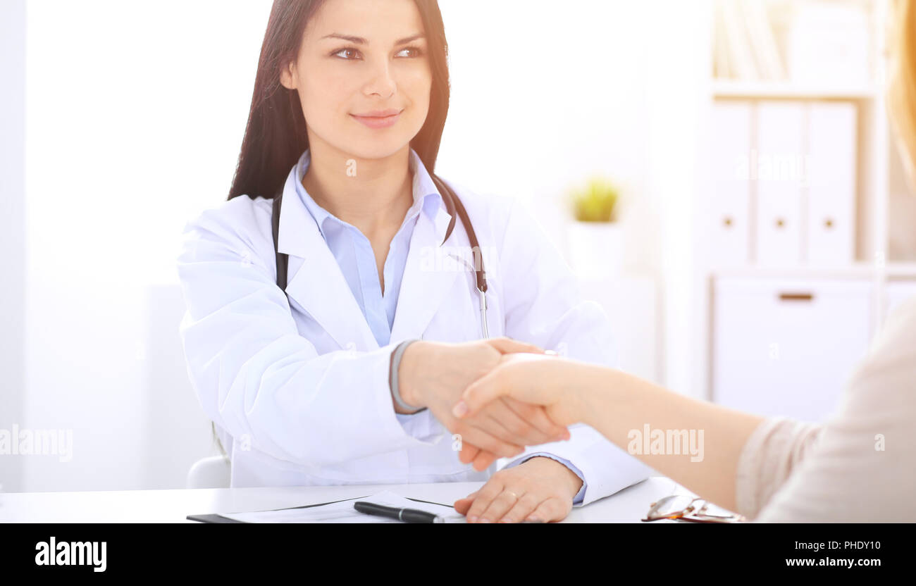 Trusting A Doctor Doctor and patient shaking hands to each other. Healthcare, medicine ...