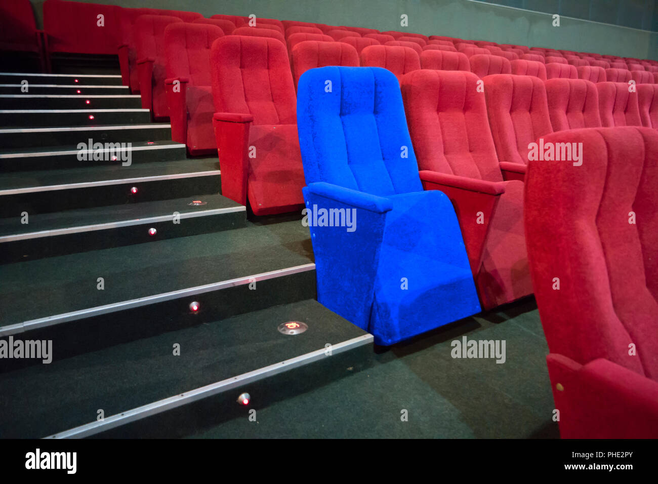 Blue chair between rows of red seats Stock Photo