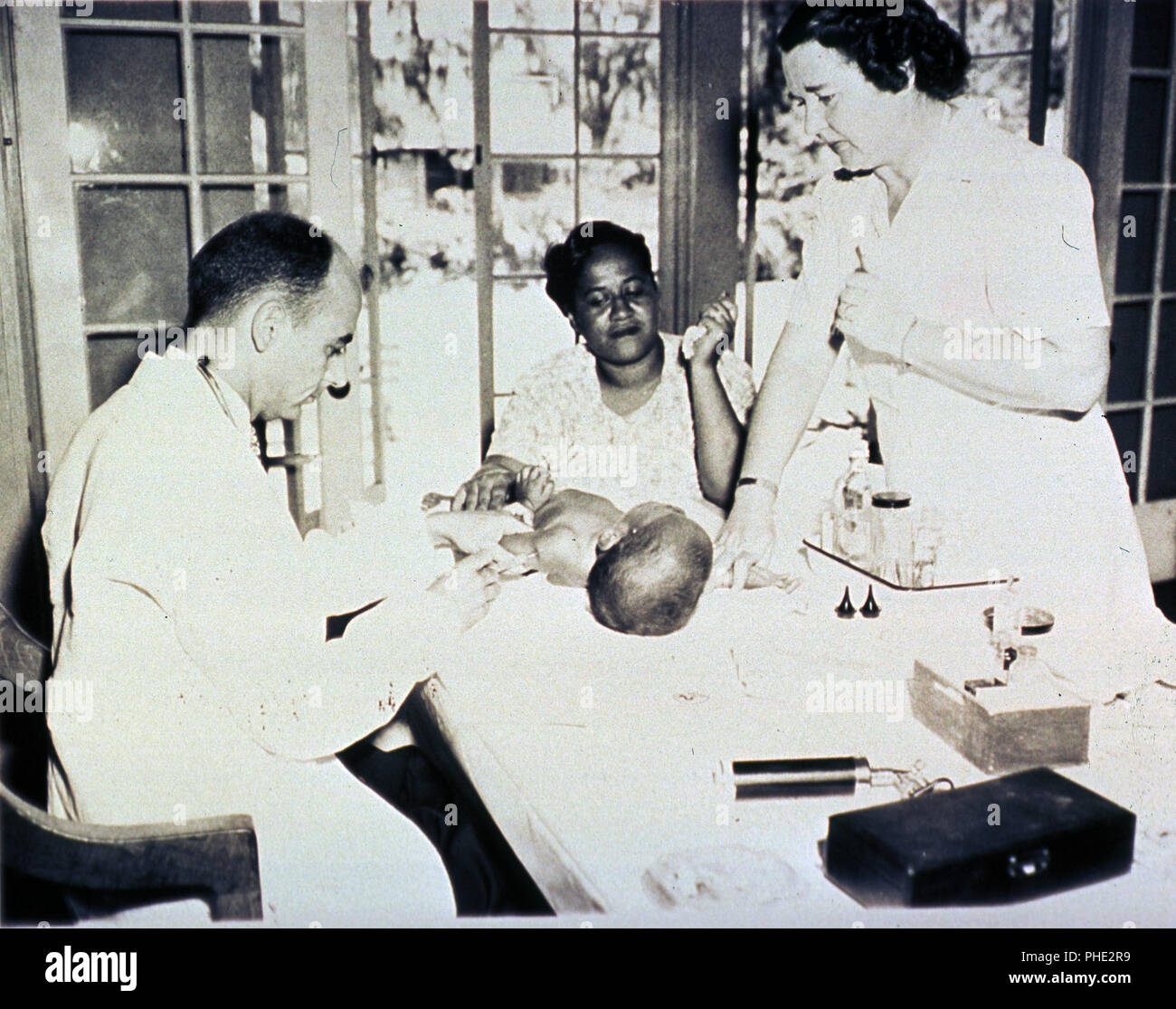 African American infant is getting an injection; a nurse and the infant ...