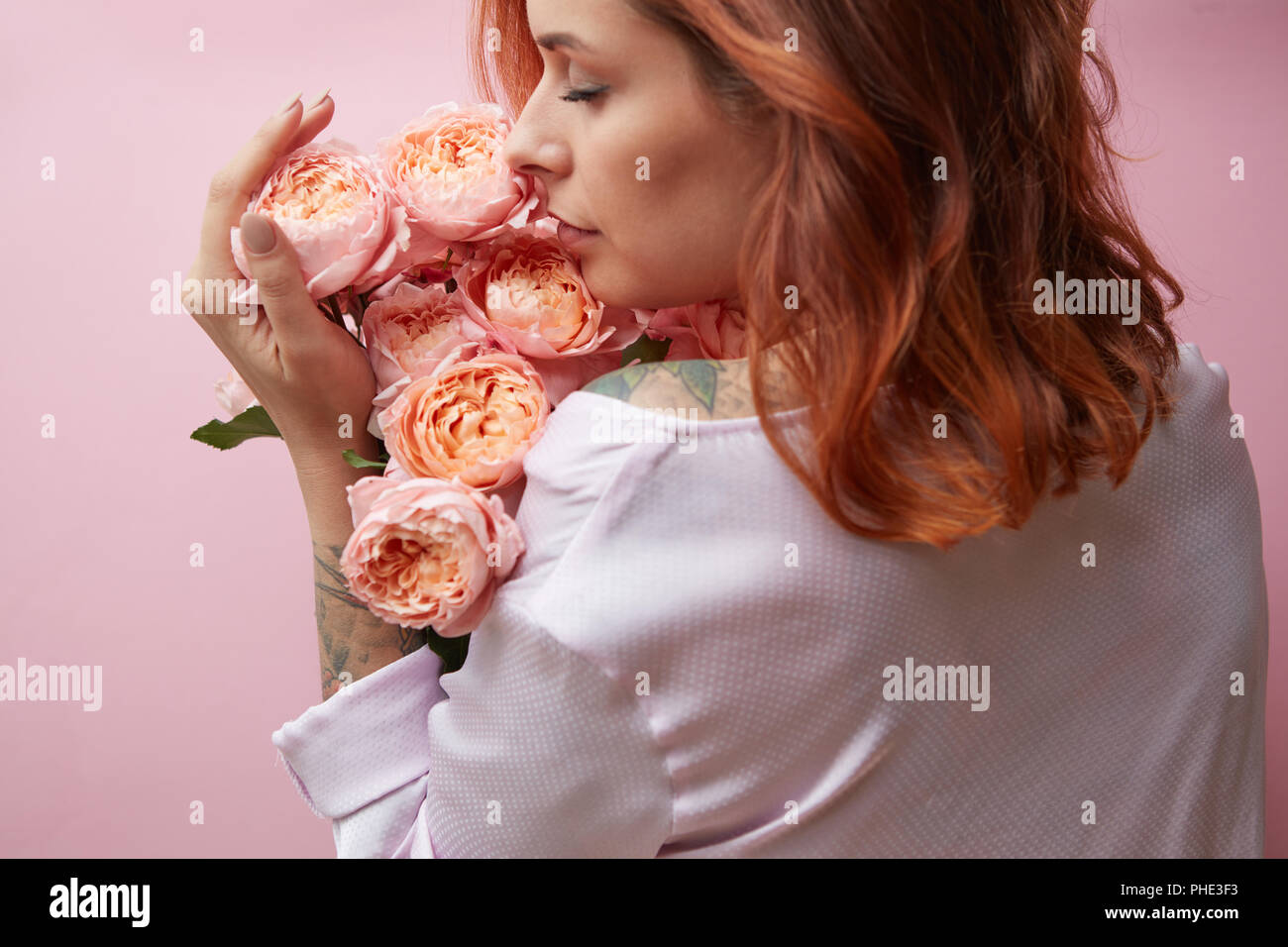 Cute woman is sniffing a bouquet of pink roses Stock Photo