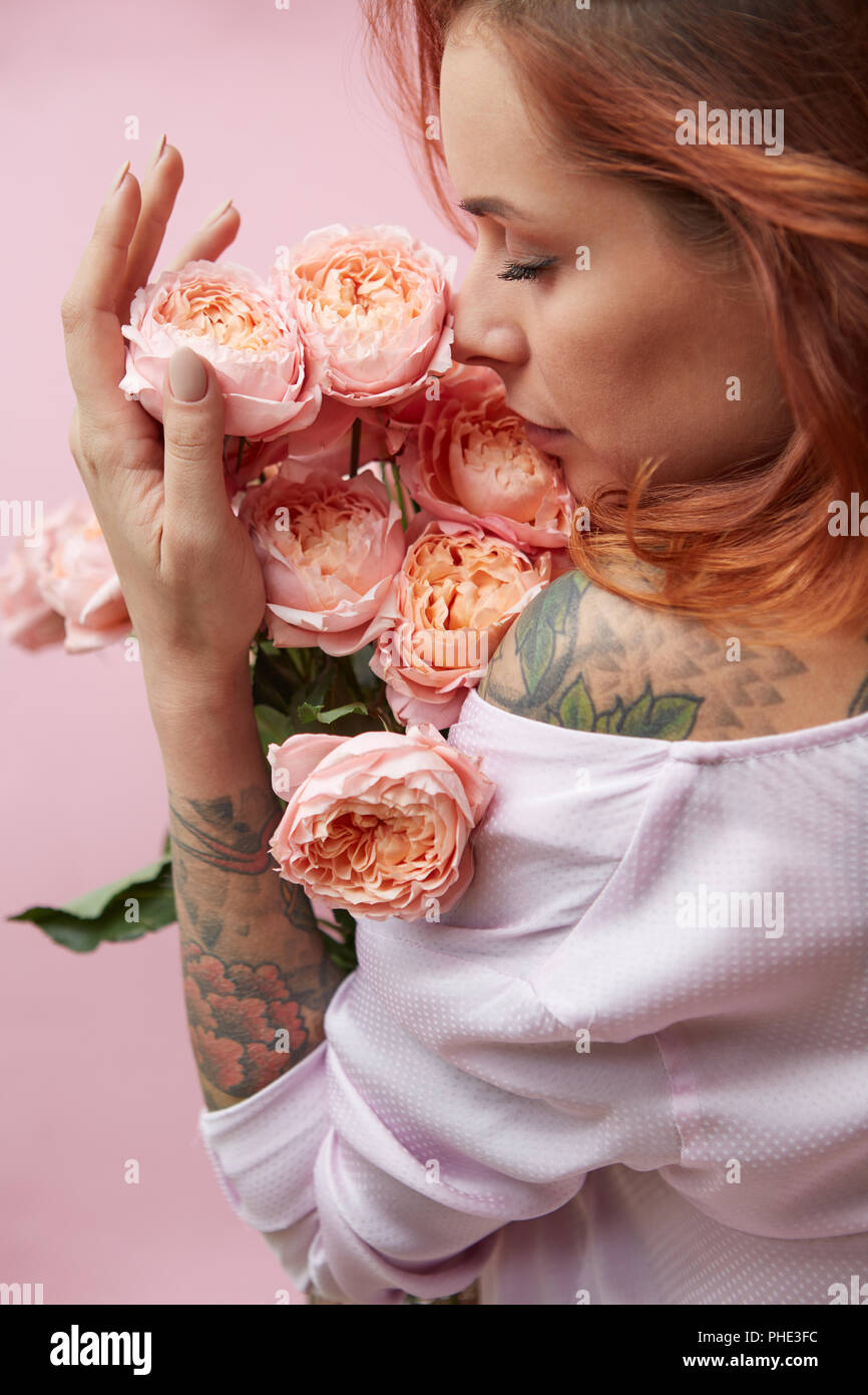 Red-haired woman sniffing a bouquet of pink ranuncukus Stock Photo