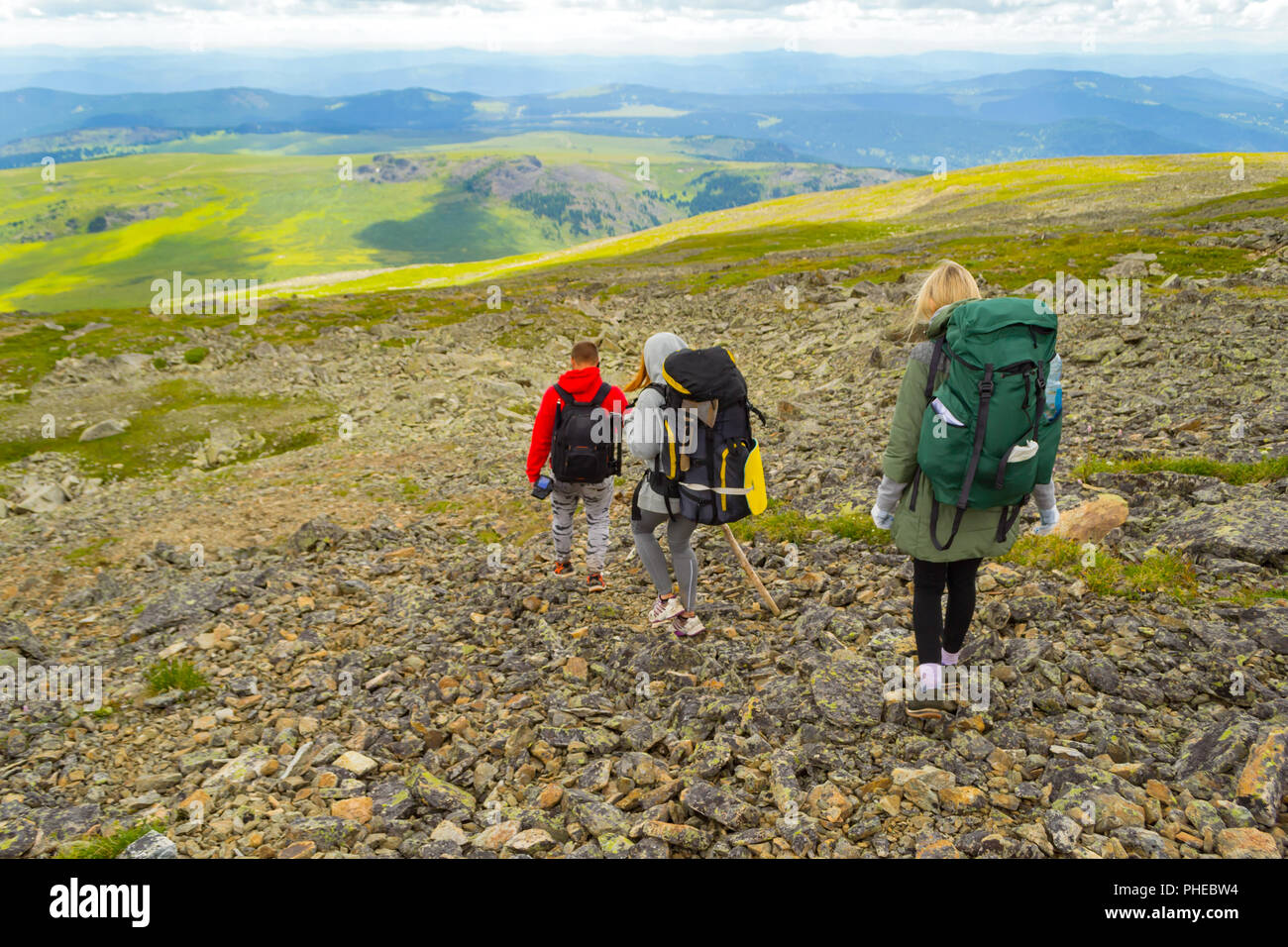 Three Tourists Two Girls And One Boy With Backpacks Go Down The Hill On The Rocks Towards The Green Fields Adventures Under The Blue Sky And Clouds I Stock Photo Alamy Three Tourists Two Girls And One Boy With Backpacks Go Down The Hill On The Rocks Towards The Green Fields Adventures Under The Blue Sky And Clouds I Stock Photo Alamy