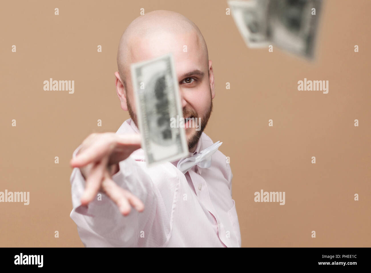 Portrait of happy handsome middle aged bald bearded businessman in white shirt standing, throw out money and looking at camera with proud rich face. s Stock Photo