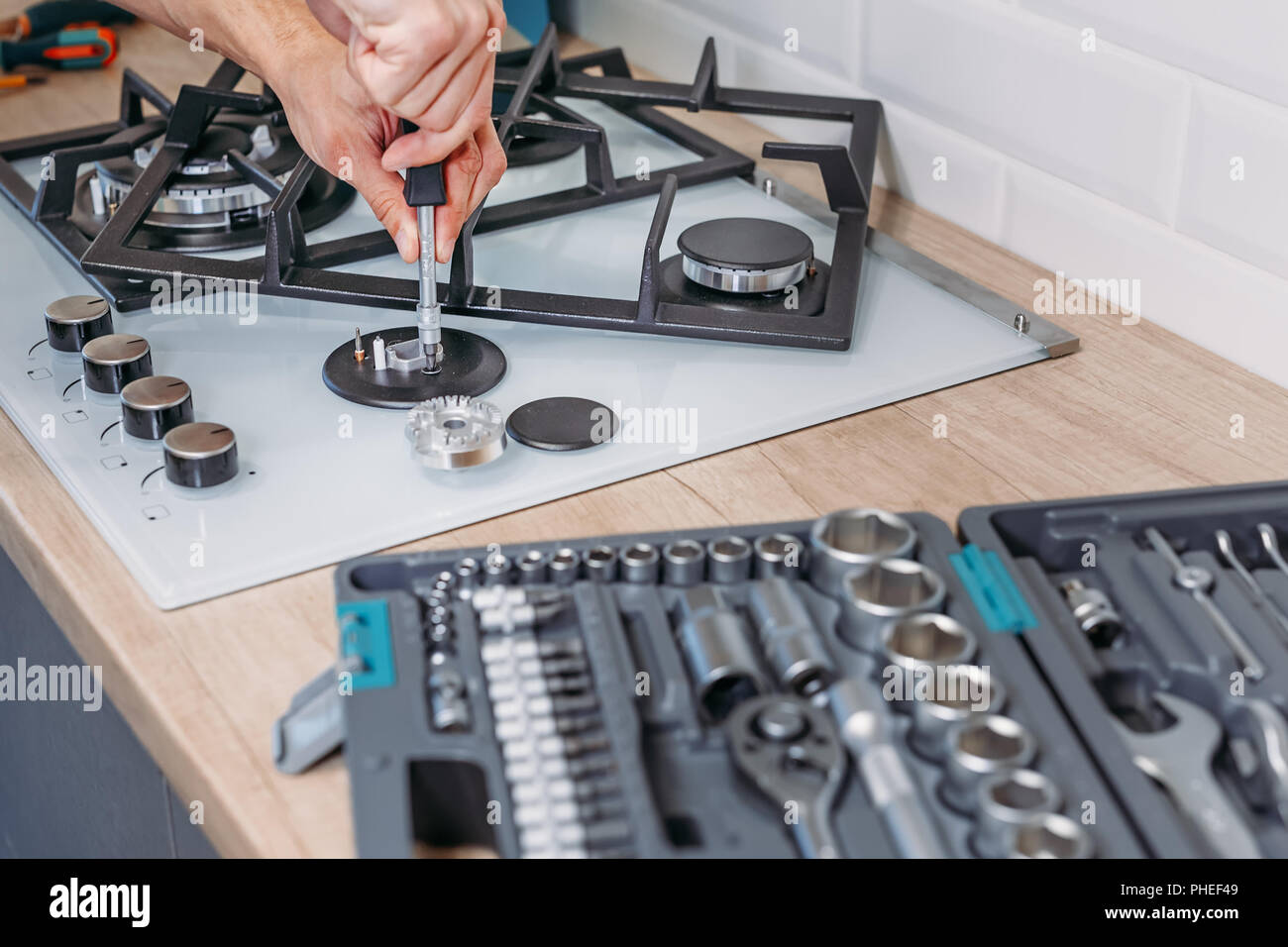 man hand repairs hotplate of gas panel with screwdriver Stock Photo