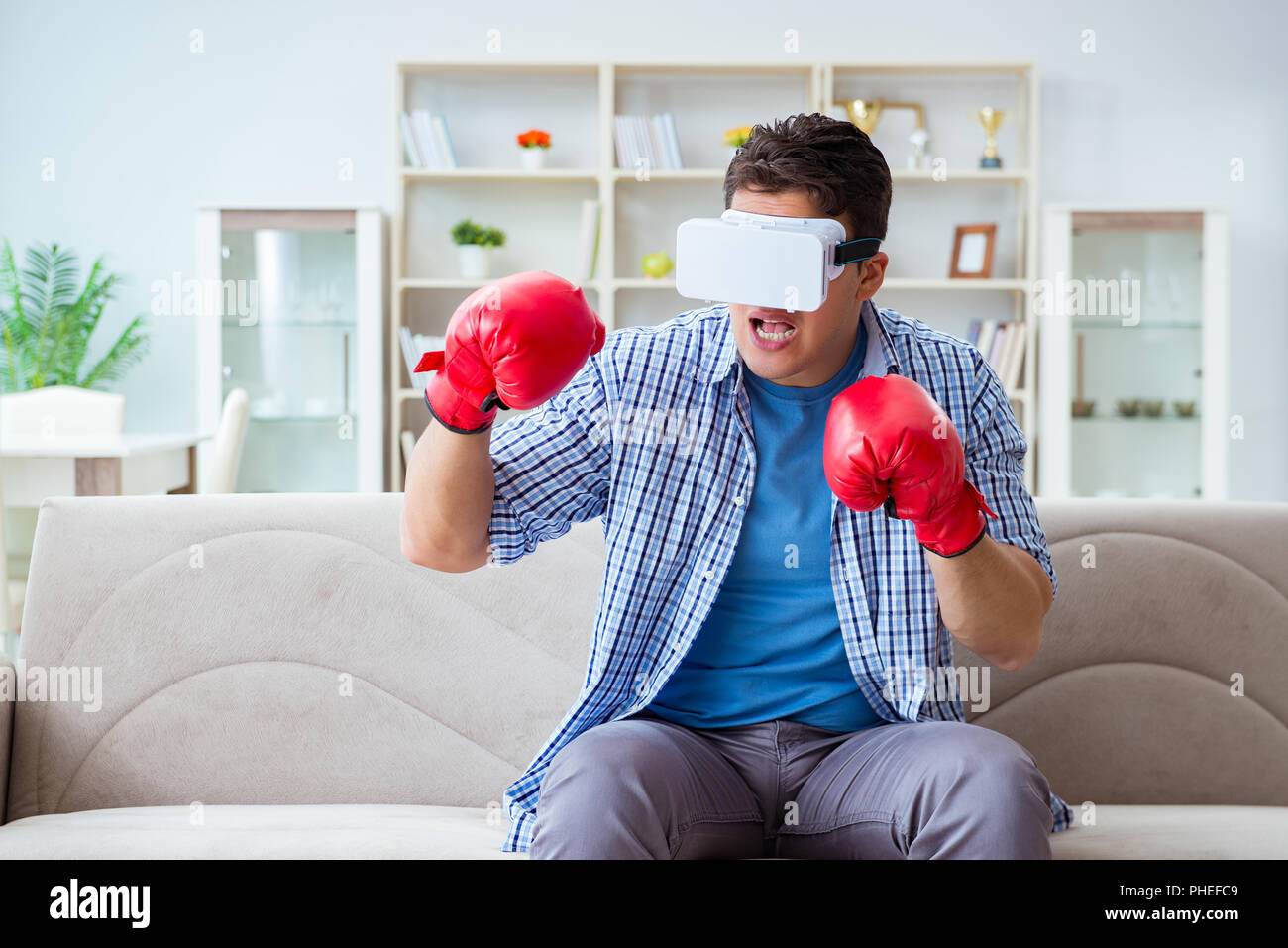 Man wearing virtual reality VR glasses playing boxing game Stock Photo