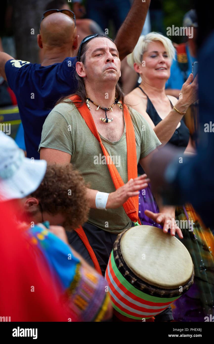 Male Caucasian percussionist playing his djembe drum bongo in the crowd at Tam Tams festival in Mount Royal Park, Montreal, Quebec, Canada. Stock Photo