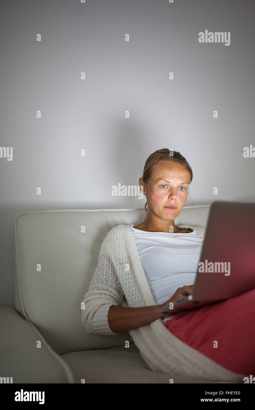 Young woman working late at night on her laptop computer, at home ...