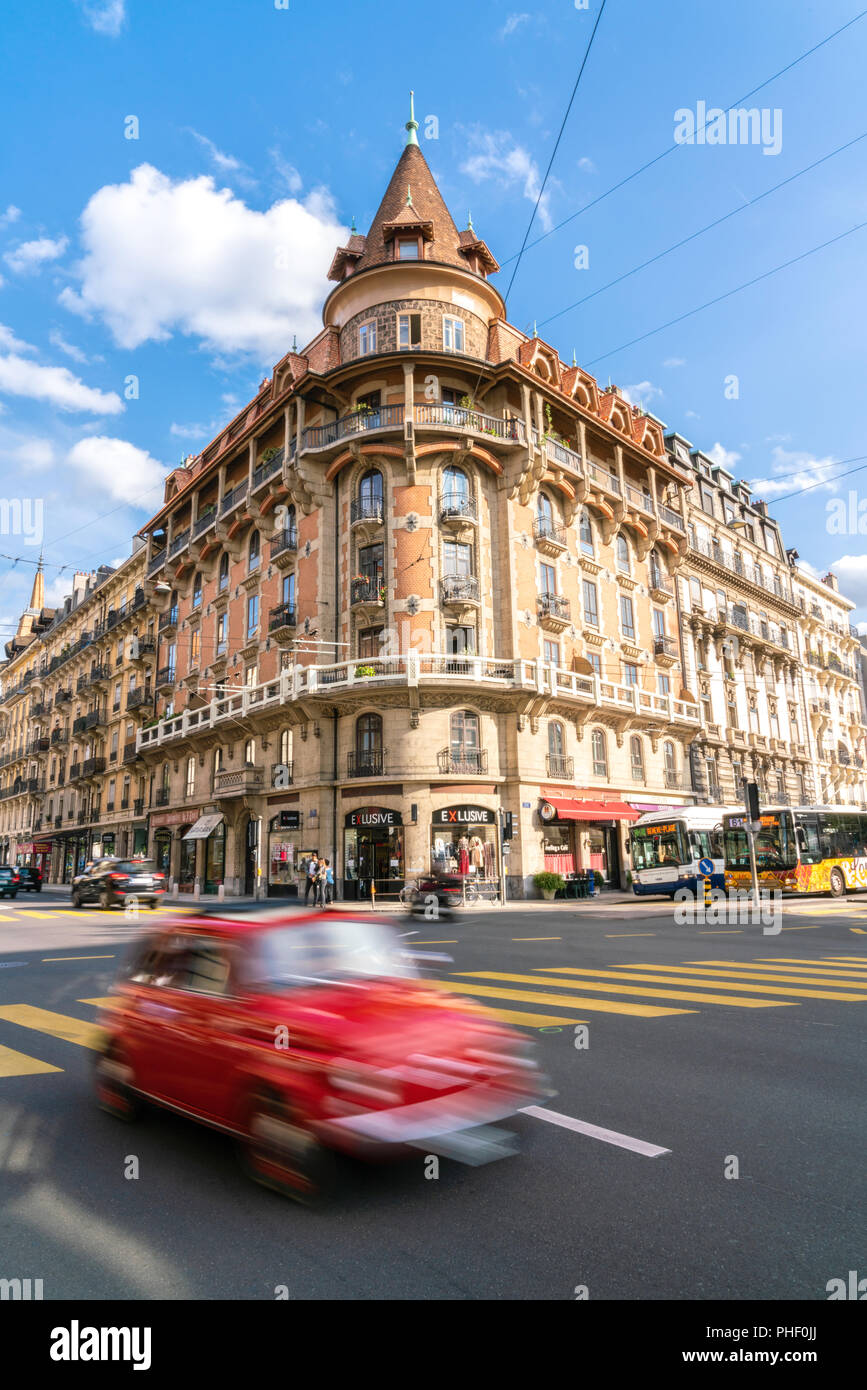 25 August 2018 - Geneva, Switzerland. Red classic car motion blurred in the street scene. Beautiful architecture building in the background Stock Photo
