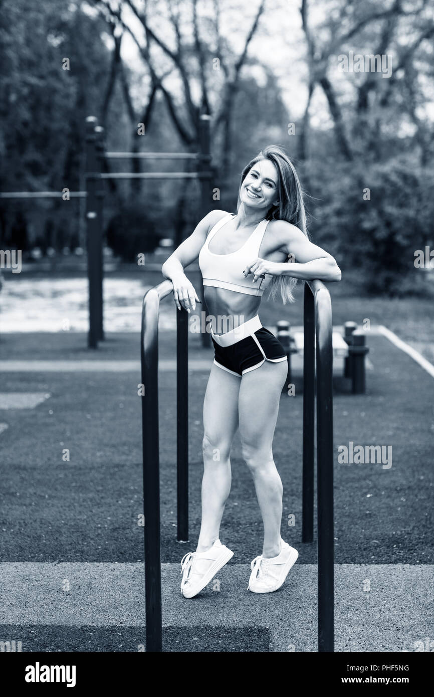 Sporty woman with perfect athletic body posing near horizontal bars. Stock Photo