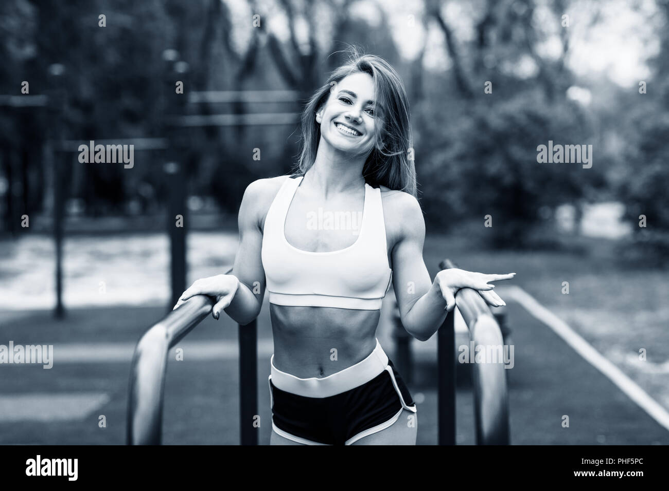 Sporty woman with perfect athletic body posing near horizontal bars. Stock Photo