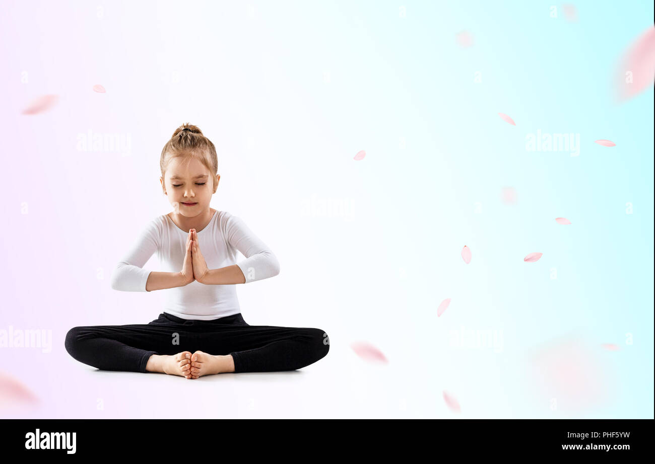 Cute little girl meditating in lotus position Stock Photo
